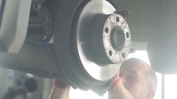Tamir istasyonunda kaldırılan otomobilin tekerlek fren ayakkabılarını değiştiren araba tamircisi - Video, Çekim