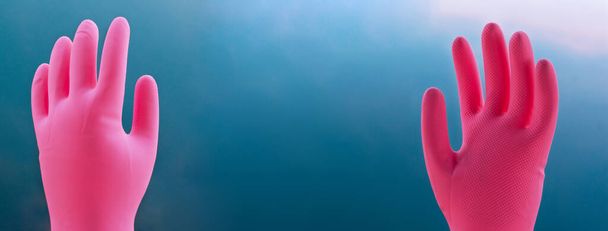 Mavi gökyüzü afişinde hijyenik sağlık veya hastalık koruması için iki renkli kauçuk pembe el eldiveni - Fotoğraf, Görsel