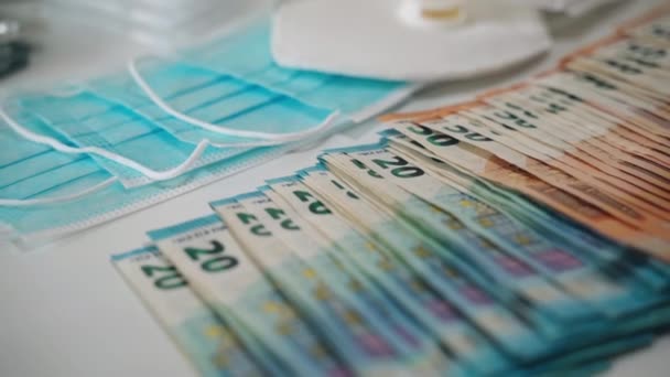Increasing prices in medical industry and development of pharmaceutical business, high cost medicine. Pile of euro banknotes scattered on the table among medical masks and different pills, capsules - Footage, Video