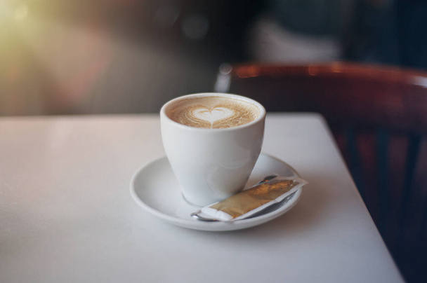Une tasse de café sur une table avec un cœur dessiné
  - Photo, image