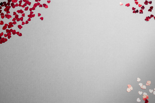 plat lag op een grijze achtergrond op Valentijnsdag, kleine rode hartjes, kopieer ruimte voor Valentijnsdag. - Foto, afbeelding