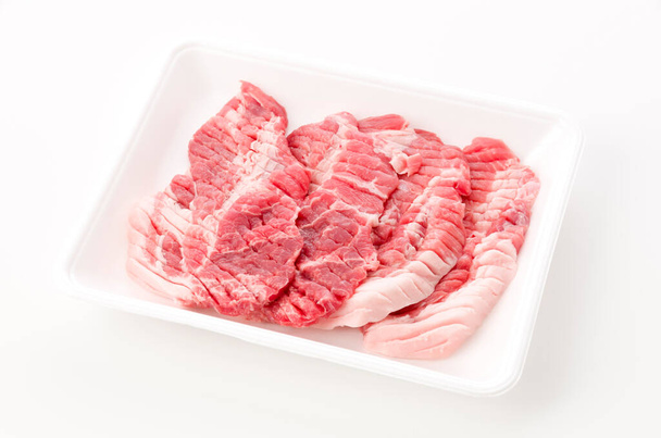 Syrové vepřové maso v pěnovém zásobníku na bílém pozadí - Fotografie, Obrázek