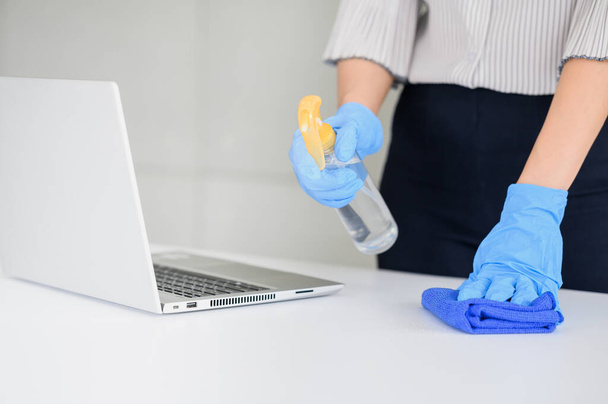 Ofisteki çalışma masasını temizlemek için eldiven, mikrofiber bez ve alkol dezenfekte spreyi kullanın. Dezenfeksiyon, temizlik ve sağlık hizmetleri, anti-Corona virüsü (COVID-19). - Fotoğraf, Görsel