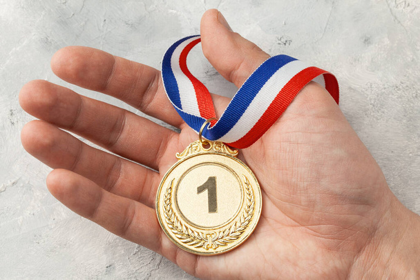 Médaille d'or. Le prix pour la première place avec un ruban qu'un homme tient dans sa main - Photo, image