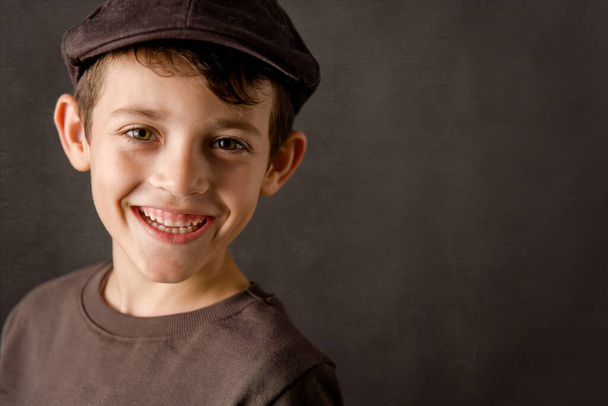 uśmiechnięty dzieciak patrzący w kamerę z brązowym vintage cap - Zdjęcie, obraz