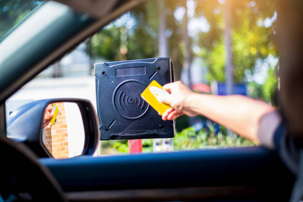 Selektive Fokussierung auf RFID-Lesegerät mit unscharfem Treiber verwenden Sie die Schlüsselkarte, um die Tür für die Sicherheit zu öffnen. Fahrer halten Karte zum Scannen an RFID-Kartenlesestation zum Öffnen der Parkhaustür. Sicherheitssystem für das Parken. - Foto, Bild