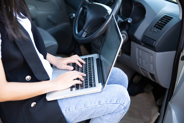 Όμορφη επιχειρηματίας χρησιμοποιώντας φορητό υπολογιστή, ενώ κάθεται στο αυτοκίνητο. - Φωτογραφία, εικόνα