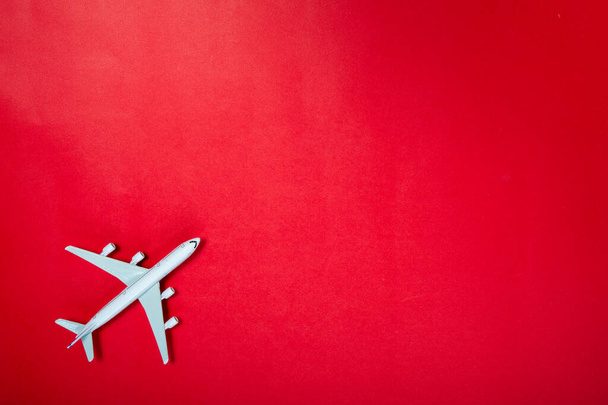 Miniature toy airplane on red background. Trip by airplane. - Foto, Imagen