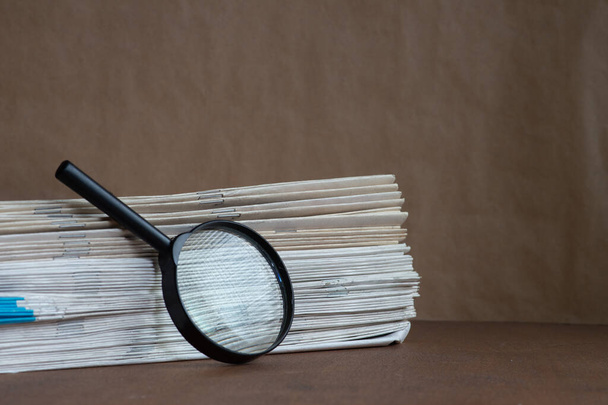 Magnifying glass with stack of documents - concept for searching for a file - 写真・画像