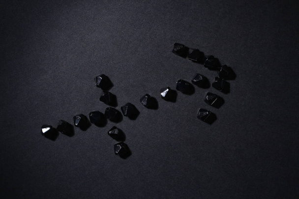 Symbol of the zodiac sign Sagittarius made by black stones on a black background. Low dark key. Vignetting lighting. Horoscope Theme - Photo, Image