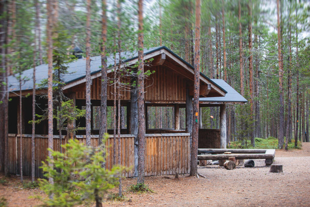 View of finnish National park oulanka with wooden wilderness hut, cabin cottage, wooden suspension bridge, wooden ladder steps, campground place, table, fire pit, bench and Oulanka, Lapland, Finland - Foto, Imagen