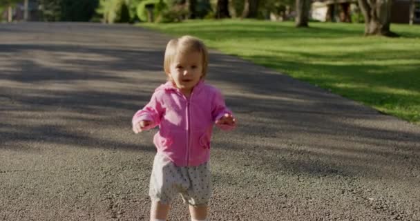 幸せな小さなかわいい女の子は、道路を歩いて - 映像、動画