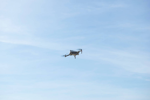 ドローンは雲を背景に青空を飛んでいます。曇った青空にドローンが頭上を飛んでいる。空に高解像度デジタルカメラとドローンクアッドコプター. - 写真・画像