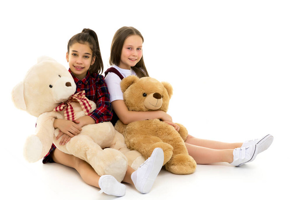 Two cheerful little girls are playing in the studio with teddy b - Foto, Bild