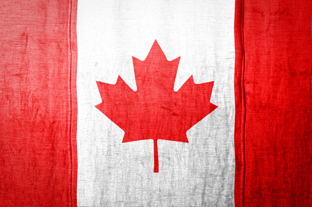 Государственный флаг Канады, изображающий цвета краски на старом текстильном материале. Флаг на фоне текстуры ткани
. - Фото, изображение