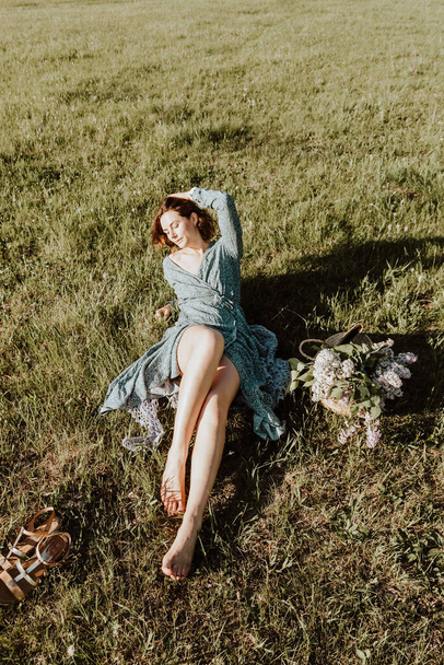 romantický portrét mladé ženy s kudrnatými vlasy v retro šatech leží na zeleném poli, v pozadí les. Tvůrčí portrét žena v přírodě. Design umění koncept - Fotografie, Obrázek