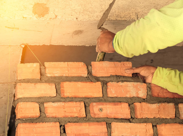 Trabajador albañil instalando mampostería de ladrillo en la pared interior
 - Foto, Imagen
