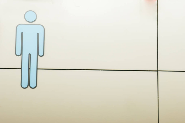 Uomo segno toilette con sfondo di cemento bianco in aeroporto
 - Foto, immagini
