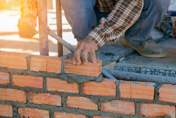 industrial bricklayer worker placing bricks on cement while building exterior walls - Foto, imagen