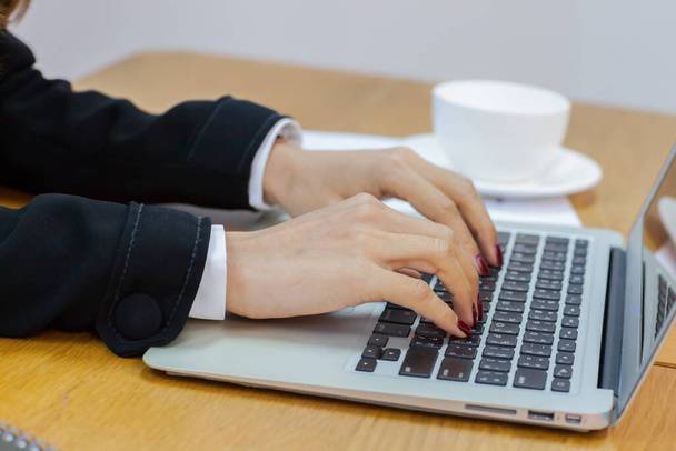 Biznesmeni ręcznie wpisują na srebrnym laptopie kolor umieszczony na stole - Zdjęcie, obraz