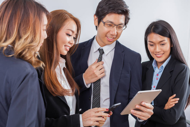 Junge Geschäftsleute stehen konzentriert am iPad und lächeln vor weißem Hintergrund - Foto, Bild