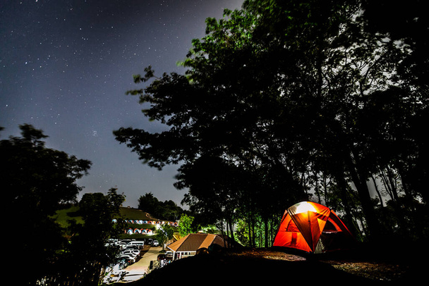 Yıldızlar tepedeki büyük ağacın tepesinde kamp çadırları olan Tayland 'ın kuzeyindeki Doi Samer Dao Ulus Parkı' nda. - Fotoğraf, Görsel