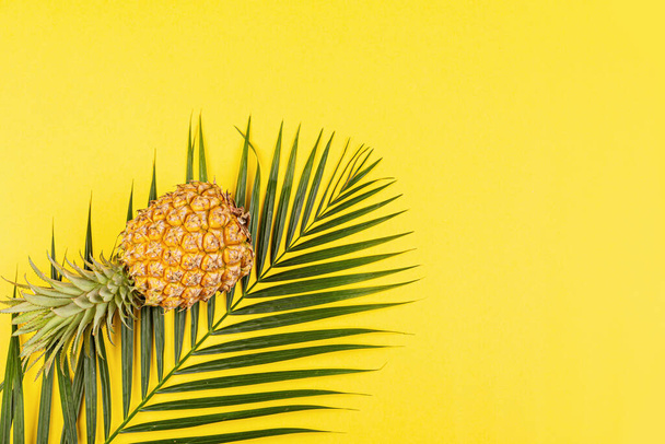 Pineapples and tropical palm leaves on yellow background. Top view, mockup, template, overhead. Summer concept. Creative flat lay with copy space - Φωτογραφία, εικόνα