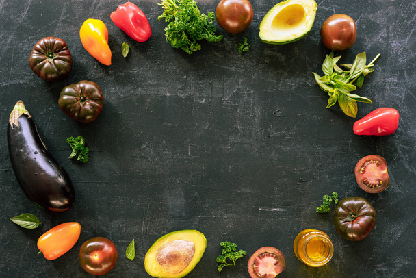 Marco de verduras y hierbas en el telón de fondo de pizarra, comida vegana saludable. Fondo negro, vista superior, plano
 - Foto, Imagen