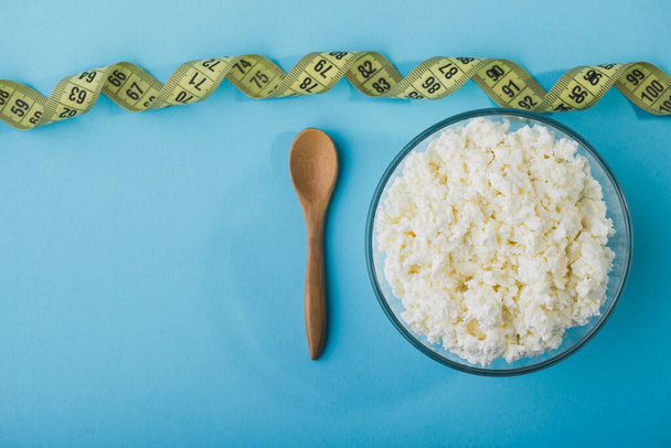 Fresh cottage cheese in a glass bowl with milk and measuring tape - Photo, Image