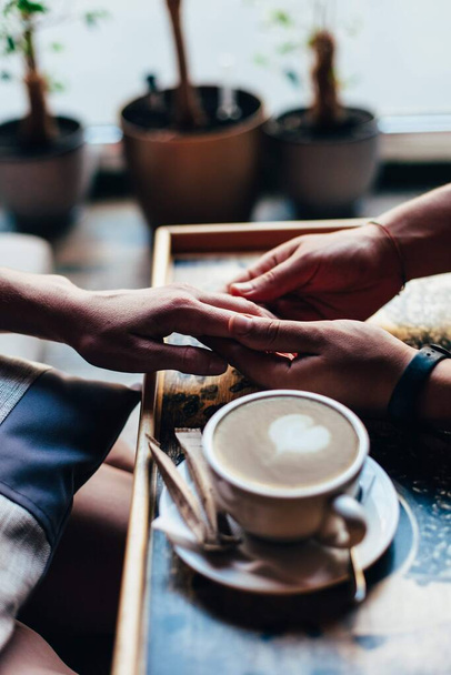 The couple in the cafe holds hands gently. A cup of coffee. - Foto, Imagem