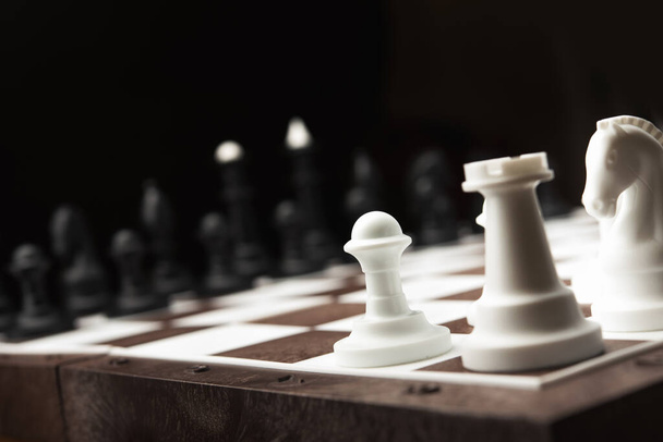 chess pieces on the board, black background  - Fotografie, Obrázek