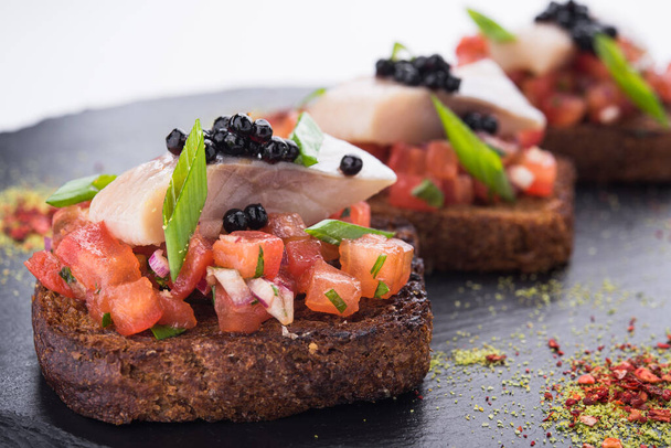 bruschetta con tomates y arenque marinado, caviar negro
 - Foto, imagen