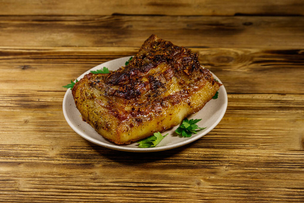 Жареная свинина в тарелке на деревянном столе - Фото, изображение