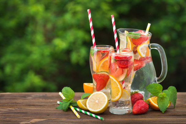 Мохіто коктейль та інгредієнти, лимон, полуниця та апельсин, на столі на відкритому повітрі
 - Фото, зображення