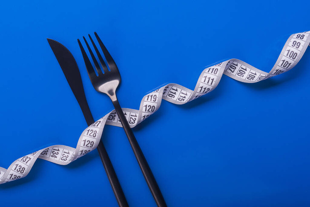 vork en mes met wit meetlint. dieetvoeding achtergrond - Foto, afbeelding