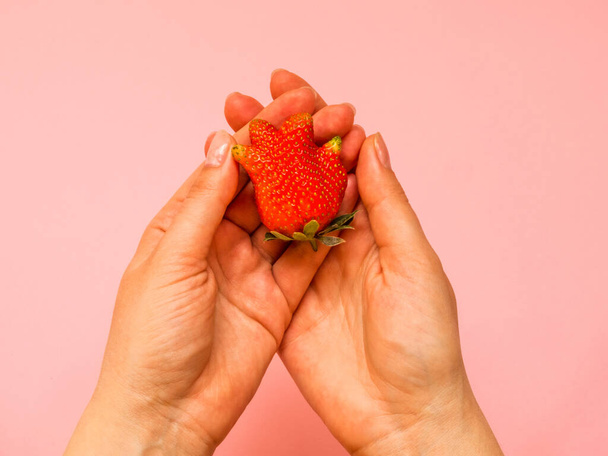 Ugly food: unusual strawberry in a woman hands - Foto, imagen