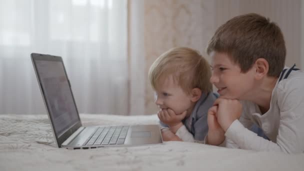 nowoczesne technologie, mali bracia dobrze się bawią, oglądają śmieszne programy na portalach społecznościowych na laptopie - Materiał filmowy, wideo