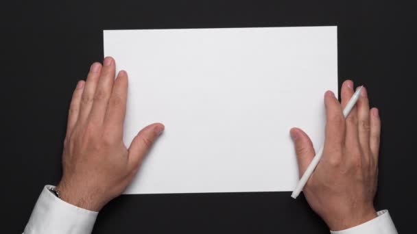 top view of a blank sheet of paper and a businessman's hands on a black table, white shirt and wrist watch - Footage, Video