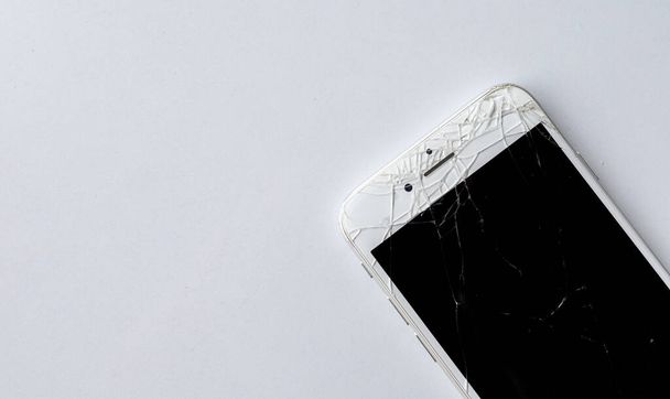 primo piano smartphone con uno schermo rotto su sfondo tavolo bianco
 - Foto, immagini
