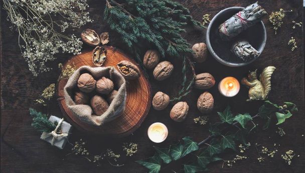 Noix en petit sac brun et autel de sorcière wiccan comme méthode de divination pour le solstice d'hiver (Noël) de Yule. Pose plate avec branches de lierre persistantes, fleurs séchées, bâtonnets de sauge, cadeaux enveloppés et cadeaux en arrière-plan
 - Photo, image