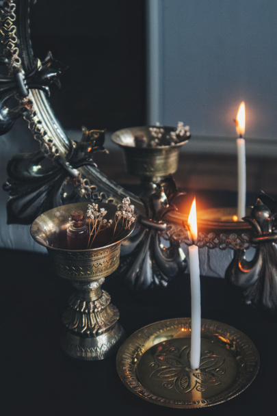 Дзеркальна магічна чаклунка - риє білою запаленою свічкою, щоб прочитати полум'я. Відбиття худої свічки палиці в темному, мотивованому старовинному дзеркалі, з золотими латунними антикварними предметами на задньому плані - тримач свічок, пальник для ладану
 - Фото, зображення