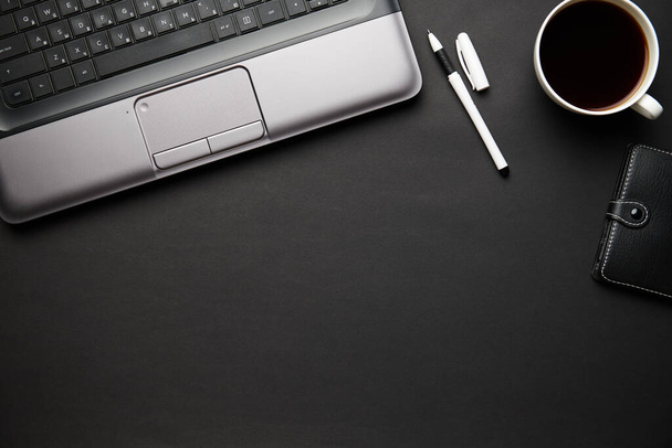 Widok góry nowoczesnego czarnego biurka z laptopem, notatnikiem, ołówkiem i wieloma rzeczami. Płaski układ stołu. Kopiuj miejsce na tekst. - Zdjęcie, obraz