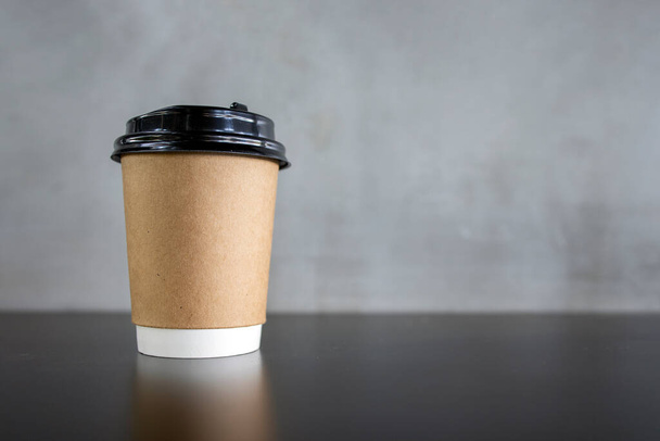 Крупный план бумажная чашка кофе на черном столе с мягким фокусом и над светом в фоновом режиме
 - Фото, изображение