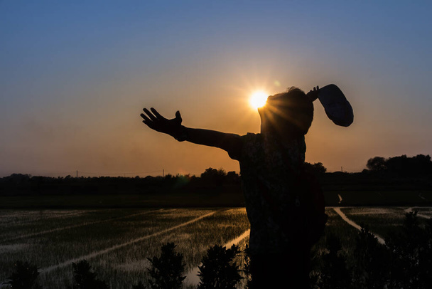silhouette of man standing with hands in a field at sunset,freedom man concep - Photo, Image