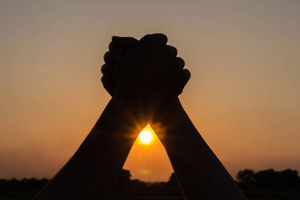 silhouette de couple tenant la main vers le haut célébrant la victoire beau fond de coucher de soleil, les gens gagnants concèdent
 - Photo, image