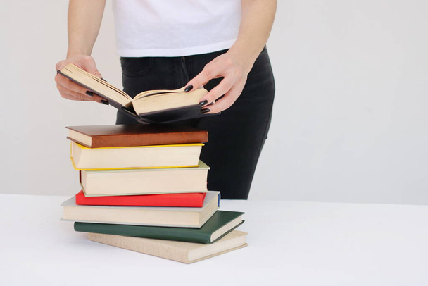  Μια όμορφη νεαρή μαθήτρια κρατά βιβλία στα χέρια της. - Φωτογραφία, εικόνα