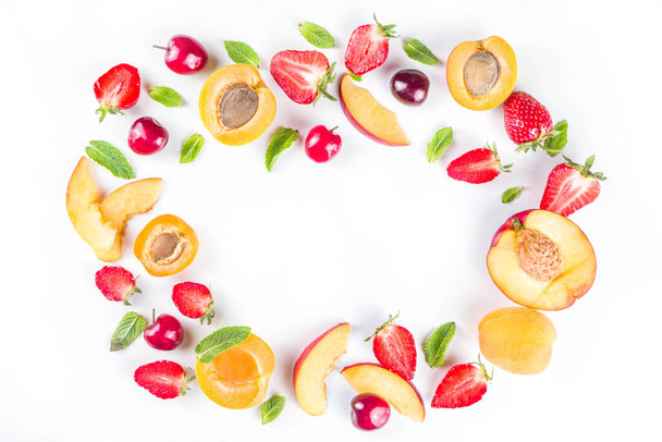 Summer background with fresh fruits and berries on white background. Set of various seasonal fruit and berry  - strawberry, apricots, peach slices, cherry, mint. Flat lay. Summer fruits concept.  - Fotó, kép