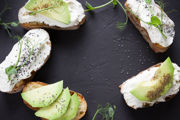 Healthy sandwiches with avocado , cream cheese and micro green. Vegan sandwiches, vegan food, healthy eating. Template with space for text , black background - Foto, Imagen