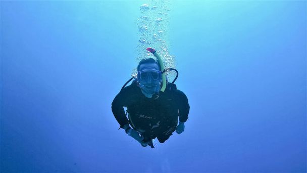 Podwodne zdjęcie uśmiechniętego nurka w wielkim błękitnym oceanie. - Zdjęcie, obraz
