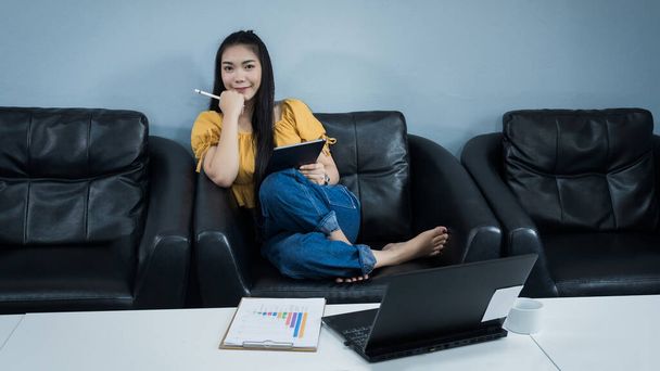 Молодая студентка использует планшет, изучающий олин, сидит дома на диване. Подростковая женщина проводит время во время пандемии ковида-19 онлайн дома. Концепция дистанционного образования
. - Фото, изображение